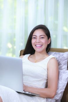 Pretty asian businesswoman looking at camera and smiling. Confident young woman working from home with laptop computer to get all her business. Positive human emotion.