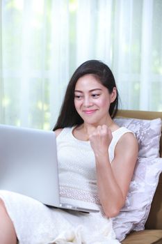 Pretty asian businesswoman working from home with laptop computer to get all her business. Positive human emotion. Action of winner or successful people.