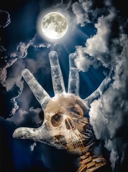 Spooky skull combined with dirty palm on nightly sky and clouds with bright full moon for halloween background. Hand up to sky. The moon taken with my own camera, no NASA images used.