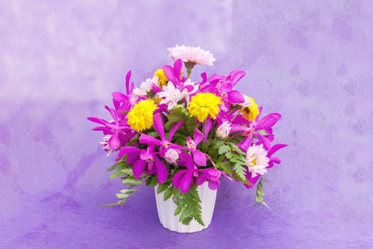 Bouquet of chrysanthemum and orchid flowers isolated on purple violet background.