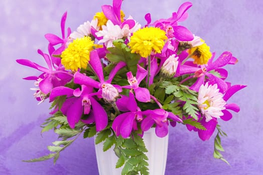 Bouquet of chrysanthemum and orchid flowers isolated on purple violet background.