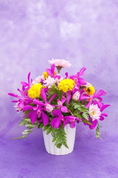 Bouquet of chrysanthemum and orchid flowers isolated on purple violet background.