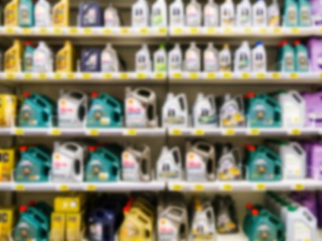 Blurred colorful motor oil bottles on shelves in supermarket as background