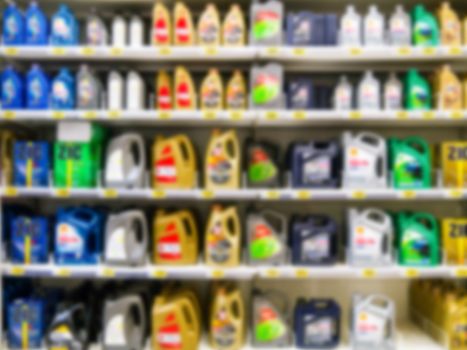 Blurred colorful motor oil bottles on shelves in supermarket as background