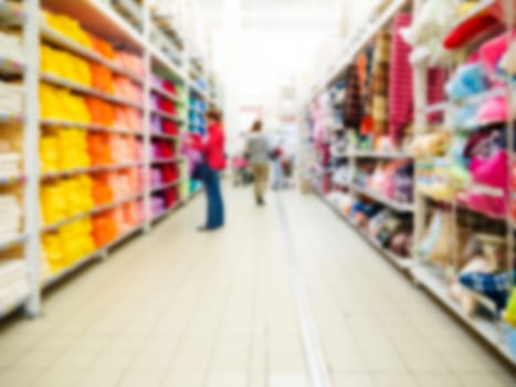 Abstract blurred supermarket aisle with colorful shelves and unrecognizable customers as background