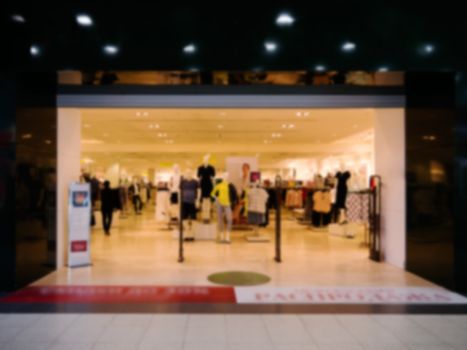 Blur image of dress store with customers and dressed mannequins