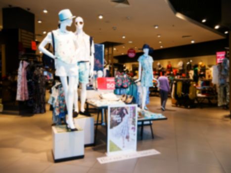 Blur image of dress store with customers and dressed mannequins.
