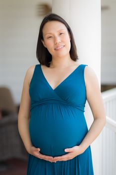 Portrait of Happy Young Pregnant Chinese Woman on the Front Porch.