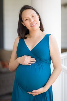 Portrait of Happy Young Pregnant Chinese Woman on the Front Porch.