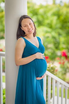 Portrait of Happy Young Pregnant Chinese Woman on the Front Porch.