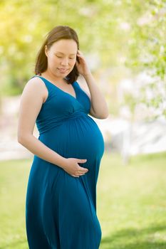 Portrait of Happy Young Pregnant Chinese Woman in the Park.