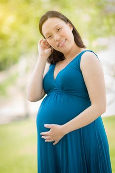 Portrait of Happy Young Pregnant Chinese Woman in the Park.