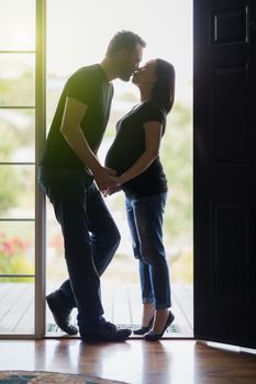 Loving Mixed Race Pregnant Couple Kissing in Doorway.