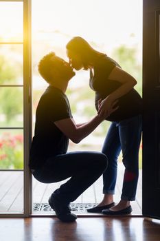 Loving Mixed Race Pregnant Couple Kissing in Doorway.