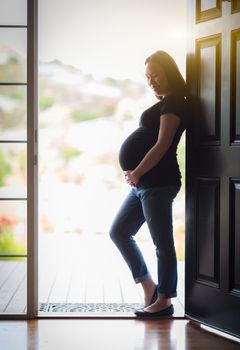 Happy Chinese Pregnant Woman Standing in Doorway.