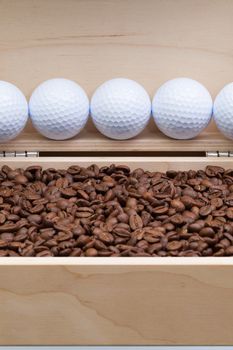 Coffee beans and golf balls in an open wooden box