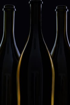 Three different bottles of wine on the black glass.