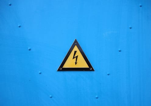 Yellow Electrical Warning Triangle Sign on Blue Background with Rivetter