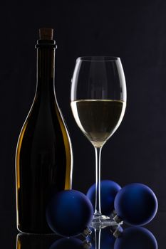 The bottle of white wine and Christmas decoration on a black glass desk