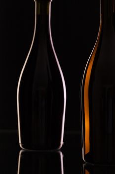 Two different bottles of wine on the black glass.