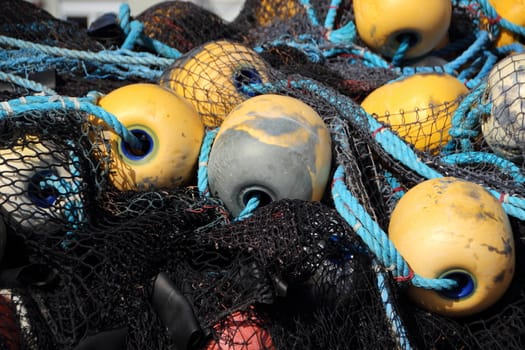 Closeup on Black Fishing Net Pile with Yellow Float in Background