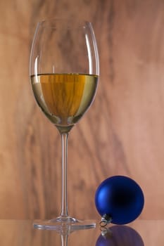 Glass of white wine and Christmas decoration on a glass desk