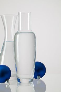 Two vases with clean water and Christmas decoration on a glass table