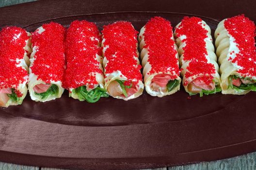 Some colorful waffle rolls with seafood lay on a wooden tray