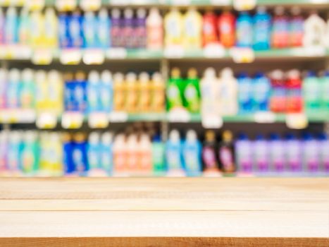 Wooden board empty table in front of blurred background. Perspective light wood over blur colorful supermarket products on shelves. Mock up for display or montage your products.