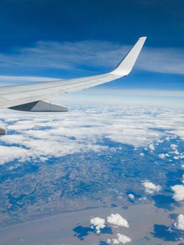 Wing of a commercial airplane flying above a coastal region.