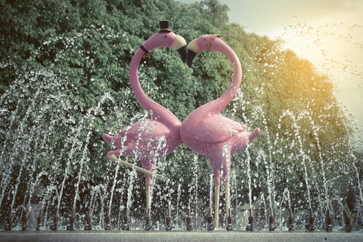 Fountain with a couple of lovely flamingos blue sky background with sunrise