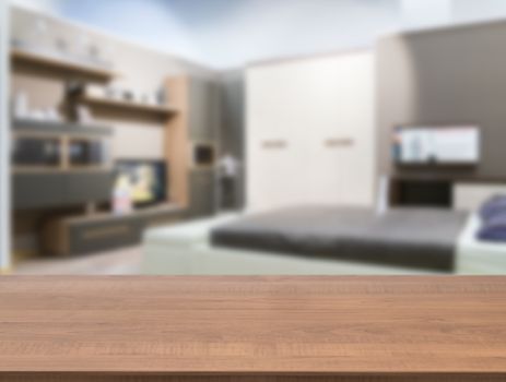 Wooden board empty table in front of blurred background. Perspective dark wood over blur in modern comfortable bedroom with white bed. Mock up for display or montage your products