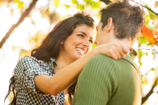 Close-up pretty girl and guy who are embracing, looking at each other, while the setting sun shines.