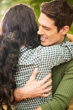 Close-up hug a boy and a girl. Handsome guy hold her brunette which you can see long black hair.