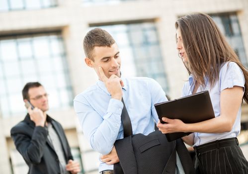 Young businessman talking to his pretty business partner in front of office building.