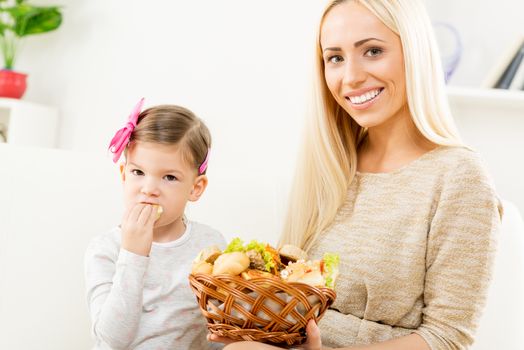 Beautiful mother gives a wicker basket with fresh pastries her daughter. With a smile looking at the camera.