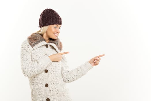 Cute girl In winter clothes pointing to something besides itself with outstretched fingers.