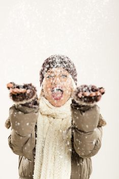 Young cheerful girl In winter clothes with hands outstretched catches snowflakes, rejoicing in the first snow.