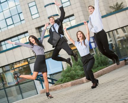 Group of young cheerful business people in front of office building, photographed at the moment of the jump.