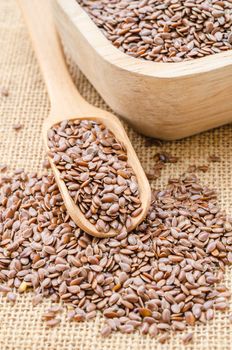 Healthy food for preventing heart diseases and overweight. Flax seeds linseed on wooden spoon burlap background