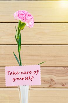 Take care of your self card with Carnation Flowers on White Vase on Wooden Table.