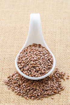 Healthy food. Flax seeds linseed on kitchen spoon burlap sack background