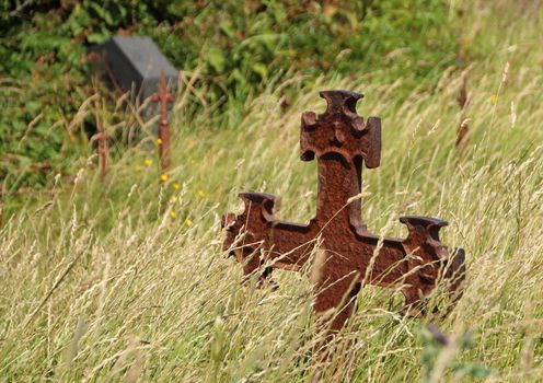 Ancient Graveyard with Single Rusty Iron Cross in Grass field