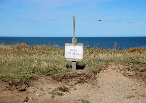 Danish Sign at Edge of Cliff warning of Earth Erosion