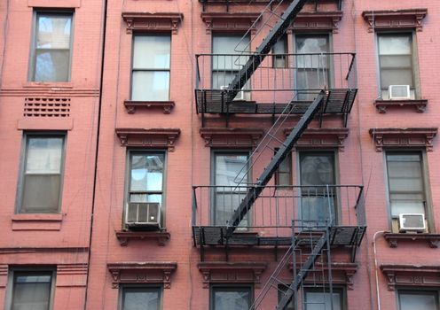 Fire Escape Steel Ladder on Urban Red Apartment House Facade in New York