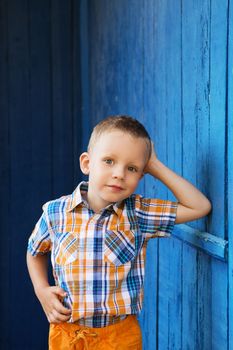 Portrait of happy joyful beautiful little boy against the old textured blue wall