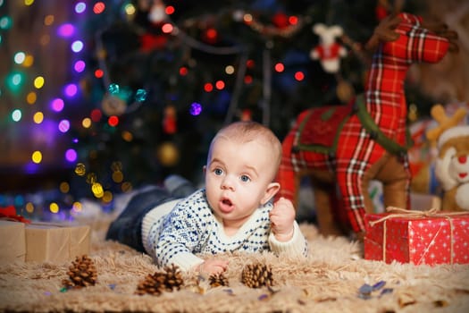 little baby boy lying on his stomach in the room with Christmas decorations