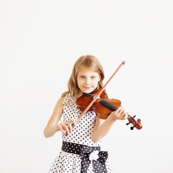 Portrait of girl with string and playing violin. Portrait of the little violinist. Beautiful gifted little girl playing on violin against the white background