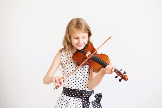 Portrait of the little violinist. Beautiful gifted little girl playing on violin against the white background