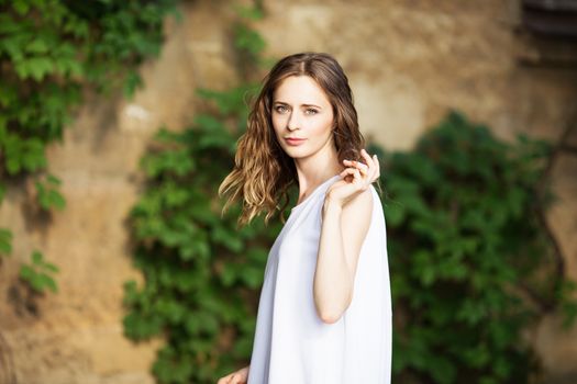 Portrait of lovely urban girl in short white dress in the street. Portrait of a happy smiling woman. Fashionable blonde girl having fun outdoors in the city